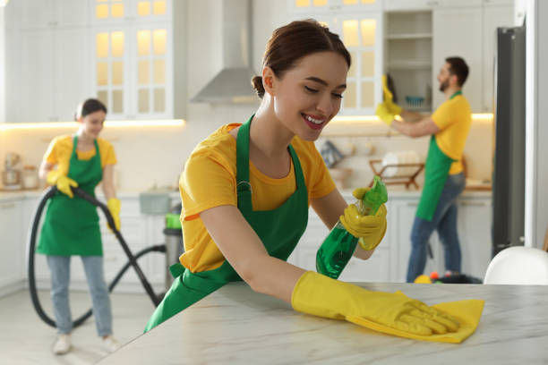 Professional cleaner wiping a kitchen table with cleaning supplies in San Antonio home.
